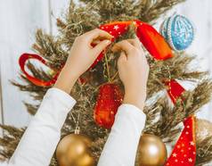 儿童手挂装饰圣诞节树孩子装修圣诞节树圣诞节树装饰红色的丝带金球蜿蜒的特写镜头