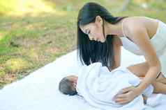 亚洲美丽的妈妈。护理新生儿婴儿谎言白色地毯花园
