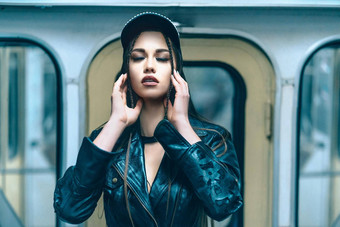 有吸引力的迷人的模型女关闭眼睛摆姿势内部地铁火车可爱的年轻的女人皮革夹克现代帽内部地铁车特写镜头肖像窗户背景