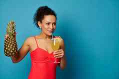 年轻的女人菠萝喝美味的异国情调的鸡尾酒稻草摆姿势蓝色的背景
