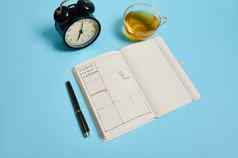 平躺时间管理的最后期限时间表概念报警时钟时间表计划组织者计划墨水笔透明的玻璃杯茶蓝色的背景空间文本