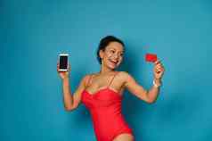 有吸引力的年轻的女人红色的游泳西装持有细胞电话手红色的空白塑料卡手