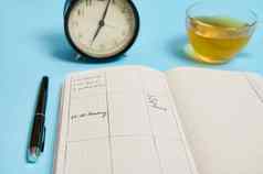 时间管理的最后期限时间表概念报警时钟时间表计划组织者计划墨水笔透明的玻璃杯茶蓝色的背景空间文本