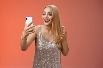 迷人的优雅的不错的金发碧眼的女孩银衣服会说话的视频调用说话智能手机显示逗乐惊讶微笑幸福的谈话兄弟姐妹显示毕业舞会装
