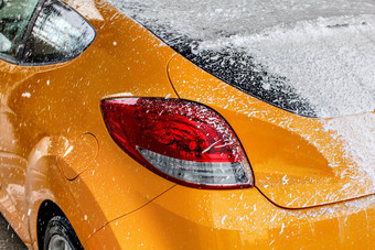 黄色的车后窗口完全覆盖厚白色洗发水泡沫洗洗车
