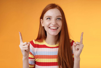 快乐快乐的红色头发的人女孩有趣的娱乐公园笑快乐指出指数手指向上享受娱乐站橙色背景逗乐咧着嘴笑快乐