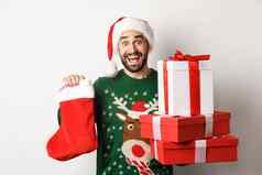 圣诞节冬天假期概念兴奋男人。持有圣诞节袜子礼物盒子庆祝一年站白色背景