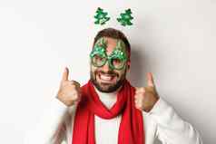 圣诞节一年庆祝活动概念特写镜头英俊的有胡子的男人。有趣的聚会，派对眼镜快乐显示拇指批准白色背景