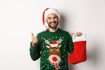 圣诞节冬天假期概念快乐很高兴男人。圣诞老人他喜欢礼物圣诞节袜子显示拇指站白色背景