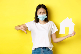 科维德真正的房地产概念失望亚洲女人医疗面具显示拇指纸房子断路站心烦意乱黄色的背景