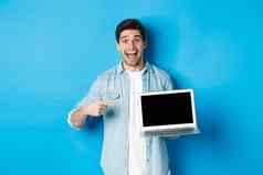 兴奋微笑男人。指出移动PC屏幕显示互联网促销提供网站广告站蓝色的背景