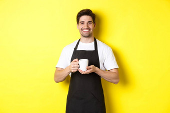英俊的咖啡师服务咖啡带杯站黑色的围裙友好的微笑