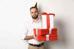 假期庆祝活动不高兴的家伙持有生日礼物失望不喜欢礼物站白色背景