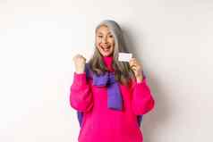 购物概念快乐的亚洲高级女人赢得奖银行显示拳头泵手势塑料信贷卡站快乐白色背景