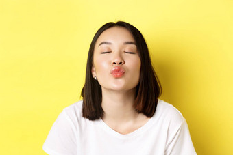 情人节一天概念关闭可爱的亚洲女孩皱纹嘴唇关闭眼睛吻站浪漫的黄色的背景
