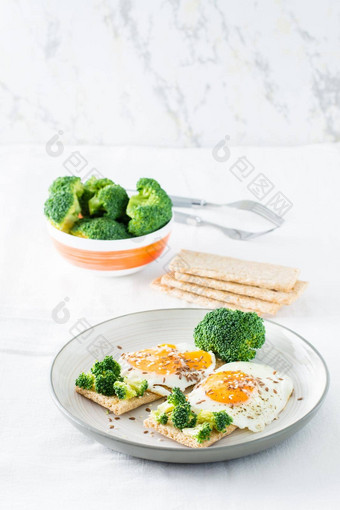 意式烤面包片炒鸡蛋西兰花粮食薄脆饼干芝麻种子亚麻籽板碗西兰花表格垂直视图