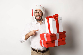 快乐圣诞节假期概念惊讶男人。收到圣诞节礼物指出礼物微笑快乐穿圣诞老人他白色背景