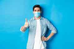概念科维德流感大流行社会距离满意的家伙医疗面具显示拇指批准站蓝色的背景