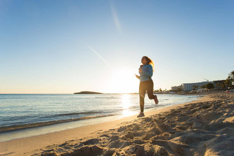 年轻的健康的生活方式健身女人运行日出海滩