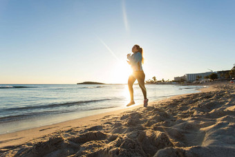 年轻的健康的生活方式健身女人运行日出海滩