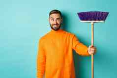 的男朋友困惑扫帚强迫清洁房子家务站不高兴光蓝色的背景