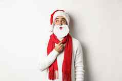 圣诞节聚会，派对庆祝活动概念有趣的男人。享受一年持有白色圣诞老人胡子面具穿红色的他工作室背景