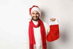 冬天假期庆祝活动概念快乐有胡子的男人。圣诞老人他持有圣诞节袜子把礼物站白色背景