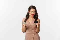 在线购物圣诞节概念优雅的年轻的女人支付互联网购买智能手机信贷卡站奢侈品衣服白色背景