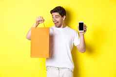 概念折扣在线银行超市夜未眠快乐的家伙买商店购物袋显示移动电话屏幕黄色的背景