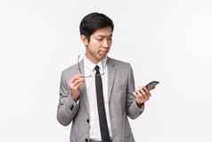 半身照肖像深思熟虑的英俊的亚洲商人使决定移动电话显示选择订单在线交付使选择购物互联网智能手机应用程序