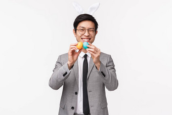 假期人庆祝活动概念半身照愚蠢的快乐年轻的英俊的亚洲男人。西装兔子耳朵眨眼微笑邀请朋友战斗画鸡蛋复活节传统