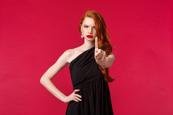 时尚奢侈品美概念不高兴时髦的红色头发的人女人豪华的时尚的黑色的衣服红色的口红显示警告标志摇晃手指责骂人坏决定