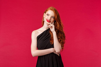 时尚奢侈品美概念肖像有创意的梦幻有吸引力的红色头发的人女黑色的优雅的衣服微笑思考想象不错的事情心红色的背景
