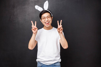 假期聚会，派对复活节概念快乐的亚洲可爱的的家伙兔子耳朵眼镜显示和平迹象卡哇伊庆祝正统的一天春天站黑色的背景快乐的