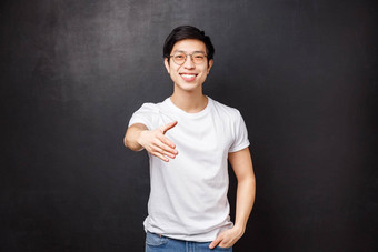 不错的满足愉快的友好的年轻的时尚的亚洲男人。眼镜t恤扩展手握手微笑会议人团队成员黑色的背景
