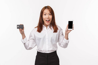 肖像友好的快乐的亚洲女人衬衫裙子持有移动电话信贷卡做广告智能手机应用程序金融银行<strong>服务站</strong>白色背景