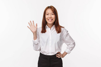 肖像友好的愉快的快乐年轻的亚洲女人挥舞着问候新来的人团队介绍使手势白色背景