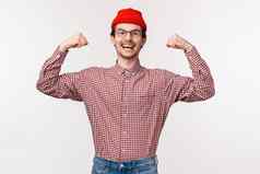 半身照肖像鼓励精力充沛年轻的自信苗条的的家伙红色的无檐小便帽眼镜flex肱二头肌显示肌肉强大的强大的站白色背景