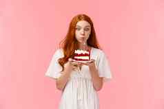 奇迹可爱的愚蠢的一厢情愿的红色头发的人女孩使生日吹蜡烛生日蛋糕集中表达式有趣的聚会庆祝家庭圆