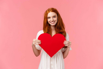 温柔爱浪漫概念浪漫的迷人的红色头发的人女朋友准备可爱的礼物情人节一天显示红色的心卡微笑表达感情同情粉红色的背景