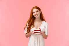 半身照肖像可爱的有爱心的红色头发的人女孩带美味的和平蛋糕厨房微笑快乐闲谈，聊天女朋友吃糖果美味的食物站粉红色的背景