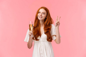 可爱的浪漫的高加索人红色头发的人女白色可爱的衣服显示和平标志非正式的问候朋友聚会，派对微笑持有玻璃香槟喝庆祝参加事件