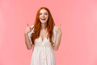半身照肖像快乐的乐观的红色头发的人女人白色衣服显示竖起<strong>大拇指</strong>微笑批准产品推荐表达积极的的意见站粉红色的背景