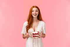 兴奋乐观的快乐诱人的红色头发的人女人白色衣服持有板美味的生日蛋糕微笑笑快乐会说话的客人聚会，派对站粉红色的背景
