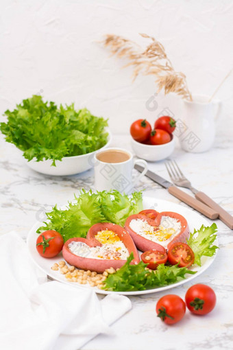 浪漫的早餐炸鸡蛋心形状的香肠生菜樱桃西红柿板表格垂直视图