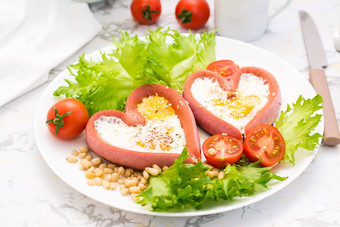 浪漫的早餐炸鸡蛋心形状的香肠生菜樱桃西红柿板表格特写镜头