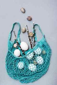 快乐复活节鸡鹌鹑鸡蛋下降蓝色的网袋猫咪柳树分支机构灰色的背景