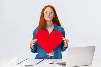 可爱的浪漫的可爱的红色头发的人女孩折叠嘴唇哇发送空气吻持有大红色的情人节卡显示爱激情祝贺女朋友周年纪念日站移动PC