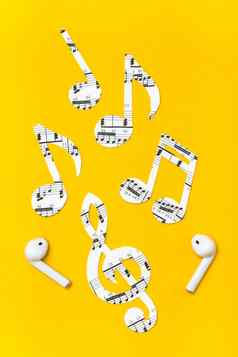无线耳机音乐笔记减少纸黄色的背景音乐模仿概念垂直视图