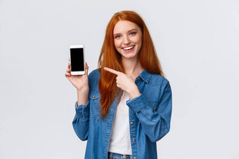 半身照肖像快乐的有魅力的红色头发的人女审查智能手机应用程序显示照片可爱的过滤器指出移动显示微笑相机白色背景